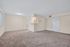 Bright and spacious living area with plush carpet, neutral walls, and adjoining kitchen entry, ideal for comfortable modern living.