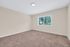 Bright and inviting room with plush carpeting and a large window offering scenic outdoor views.