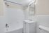 Bright and modern bathroom featuring sleek fixtures, elegant white tile, and a stylish vanity with ample storage.