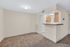 Cozy living area with plush carpet and a sleek breakfast bar leading to a modern kitchen.