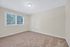 Bright, carpeted room with large window and neutral walls, perfect for a cozy bedroom or office space.