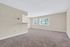 Bright and spacious room featuring neutral walls, large windows with lush green views, and plush carpeting, offering a serene living experience.