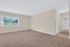 Bright and spacious room with plush carpeting, large window with scenic views, and access to bathroom, ideal for cozy living.