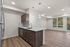 Bright and modern open-concept kitchen and living space with sleek appliances, elegant pendant lighting, and stylish hardwood floors, offering a stunning view of lush greenery.