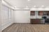 Modern apartment interior showcasing a sleek kitchen with stainless steel appliances, elegant wooden cabinetry, and large bright windows with blinds.