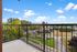 Charming balcony view showcasing scenic neighborhood, lush trees, and clear blue skies.