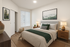 Inviting bedroom with cozy bedding, stylish wooden furniture, and serene forest artwork creating a calm atmosphere.