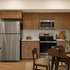 Modern kitchen with sleek stainless steel appliances, stylish wooden cabinetry, and elegant dining table for cozy gatherings.