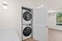 Bright open laundry area with modern stacked washer and dryer in a sleek apartment setting.