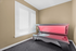 Modern room featuring a sleek tanning bed with a vibrant red glow beside a large window with white blinds.