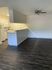 Chic open-plan living area with modern kitchen, sleek dark wood flooring, and ceiling fan, perfect for contemporary living.