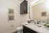 Elegant bathroom showcasing a sleek vanity, large mirror, and modern fixtures with stylish wall art and ambient lighting.