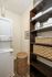 Chic laundry space featuring a modern stacked washer and dryer, elegant shelving with woven baskets, and neatly arranged towels.