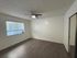 Bright and spacious bedroom with modern flooring, large window, and sleek ceiling fan.
