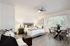 Modern studio apartment with cozy bed, stylish dining area, and ample natural light from large window.
