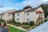 Charming two-story apartment building with well-maintained landscaping and convenient exterior staircases on a sunny day.