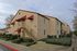 Charming apartment complex with red accents and lush landscaping, offering spacious living in a welcoming community.