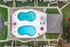 Elegant aerial view of two luxurious swimming pools with surrounding lounge chairs and vibrant red umbrellas in a beautifully landscaped apartment complex.