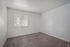 Bright and inviting room with carpeting and a large window, perfect for a cozy and comfortable bedroom setup.