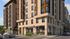 Modern apartment building with brick facade, large windows, and street-level shops.