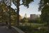Scenic view of a lush urban park with tall buildings in the background, surrounded by vibrant green foliage.