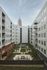 Modern apartment complex courtyard with landscaped gardens and a distant skyscraper view.