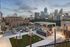 Stunning rooftop lounge with city skyline view, featuring modern seating, fire pits, and outdoor dining area.
