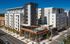 Modern urban apartment complex with distinctive architecture, featuring a rooftop pool and terrace.