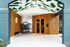 Vibrant apartment entrance with modern wood paneling, eye-catching orange door, and artistic ceiling design.