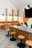 Chic and modern cafe interior with vibrant orange seating, wooden accents, and a sleek communal counter, offering a cozy and inviting atmosphere.