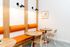 Chic seating area with vibrant orange cushions, stylish wood accents, and modern lighting, perfect for cozy gatherings.