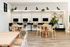 Modern apartment co-working space with sleek wooden tables, comfortable chairs, and stylish wall decor, ideal for productive work and collaboration.