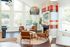 Charming living area with natural light, featuring modern leather chairs, a colorful brick fireplace, and stylish decor.