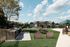 Charming outdoor community space featuring BBQ grills, picnic tables, and recreational games, perfect for social gatherings under a bright blue sky.