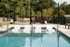 Inviting outdoor pool area with sleek pool loungers and stylish seating, surrounded by lush greenery and a modern dining space.