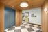 Modern apartment lobby with stylish wood paneling, sleek blue elevator doors, and eye-catching geometric flooring.