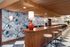 Chic and vibrant bar area with artistic mural, wooden accents, stylish seating, and modern lighting.