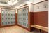 Modern locker room with sleek metal lockers and stylish wood-accented bench, featuring bright overhead lighting and unique wall hooks.