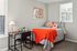 Cozy bedroom with a stylish single bed adorned with vibrant orange accents, complemented by a modern desk and chic decor.