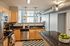 Modern kitchen with sleek wooden cabinets, granite countertops, and stainless steel appliances, featuring natural light and industrial chic venting.