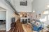 Chic modern living room with high ceilings, trendy ductwork, and elegant lighting features, complete with a stylish open-concept kitchen and dining area.