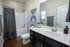 Contemporary bathroom with elegant wood flooring, stylish dark vanity, and ambient lighting.