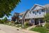 Charming suburban row of modern townhouses with manicured lawns and a serene ambiance, featuring vibrant gardens and a sunny sidewalk perfect for leisurely strolls.