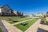 Charming apartment complex with vibrant facades, featuring a sunny communal courtyard equipped with playing fields in a serene neighborhood setting.