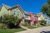Charming row of colorful townhouses with well-maintained lawns and vibrant facades basking in the sunlight.