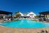 Luxurious poolside retreat featuring crystal-clear water, modern lounge chairs, and elegant pergolas against a bright, cloudless sky.