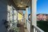 Charming balcony with a ceiling fan, overlooking a picturesque neighborhood with colorful houses and lush greenery.