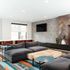 Stylish modern living room with plush gray sofas, geometric accent wall, and vibrant patterned carpet, offering a chic and cozy ambiance.
