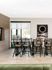 Elegant dining area with stylish wooden chairs and a modern table, enhanced by natural light and artistic decor, offering a perfect blend of comfort and design.