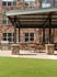 Charming patio area with lush green space, stone accents, and a sleek barbecue setup for outdoor relaxation.